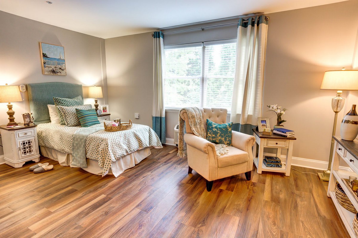 A cozy bedroom with stylish furnishings and natural light streaming through a large window.
