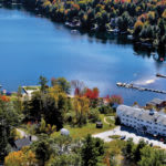 A serene aerial view of a lakeside area with colorful autumn trees and a dock.