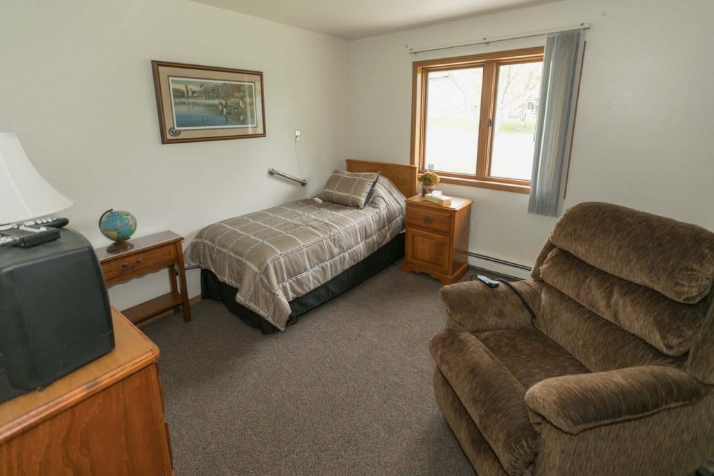 A cozy bedroom with a single bed and comfortable armchair.