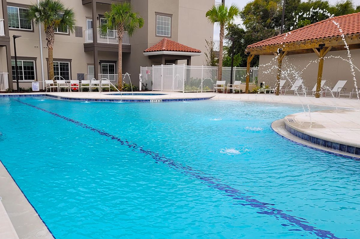 A serene outdoor swimming pool surrounded by palm trees and resort buildings.
