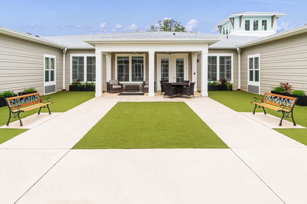 A spacious courtyard with a lawn and outdoor seating in front of a modern house.