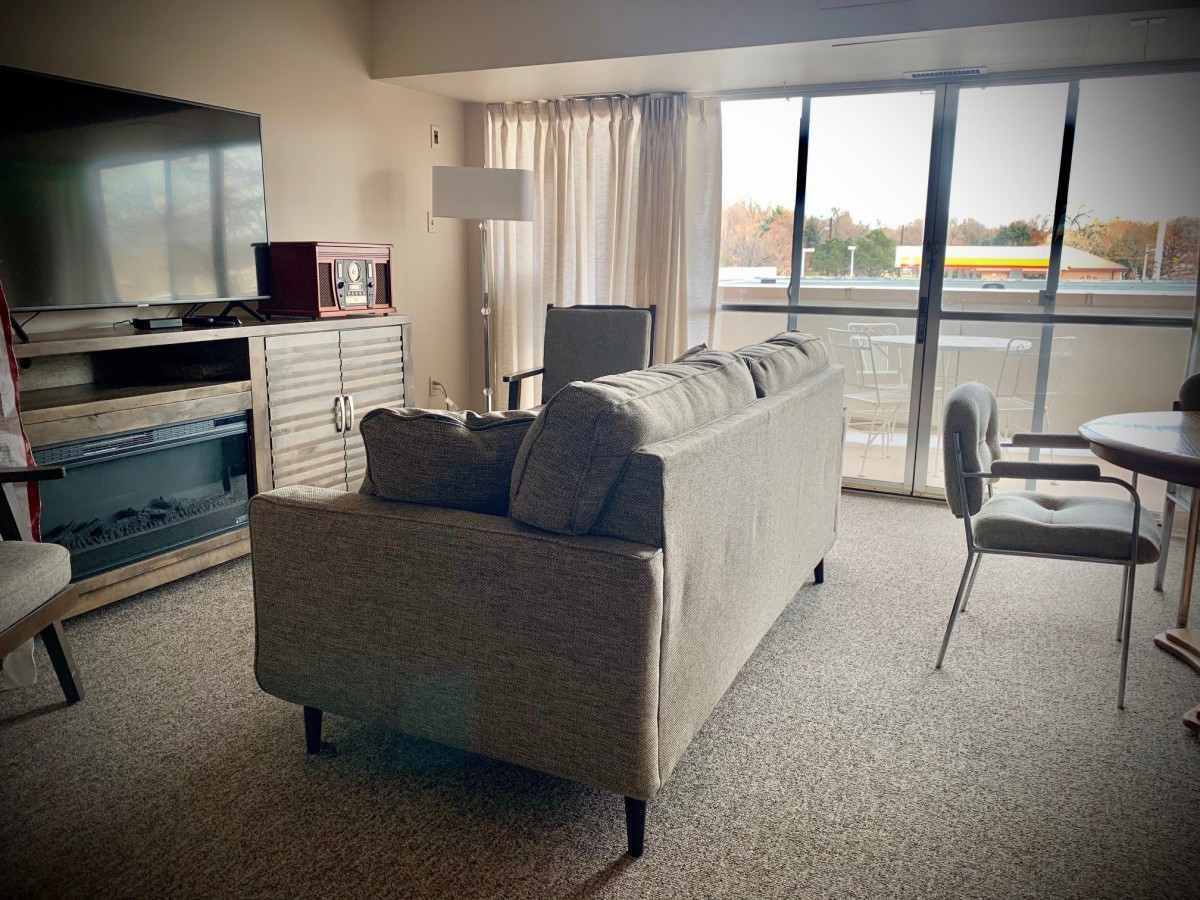 A cozy living room with a sofa, lamp, and large window.
