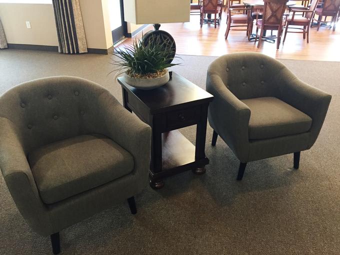 A cozy seating arrangement featuring two armchairs and a side table with a lamp and plant.
