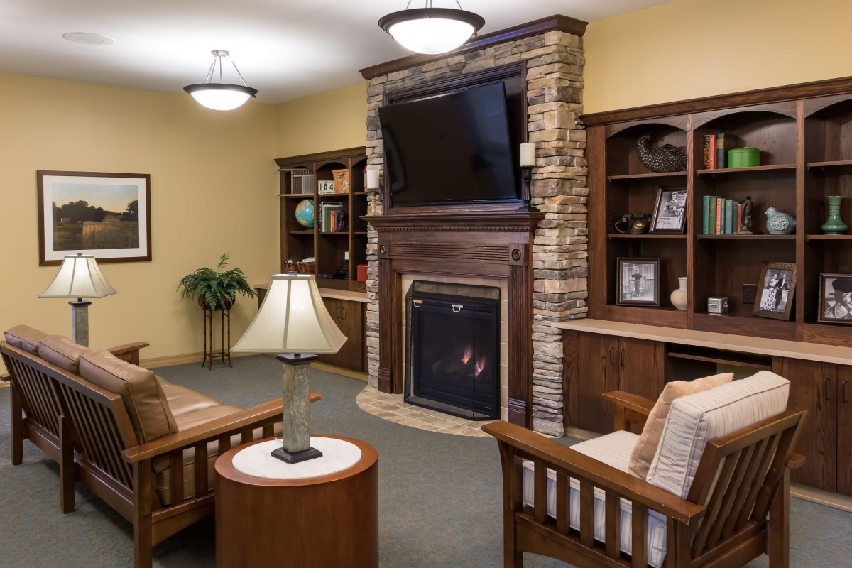A cozy living room with a fireplace, television, and built-in bookshelves.