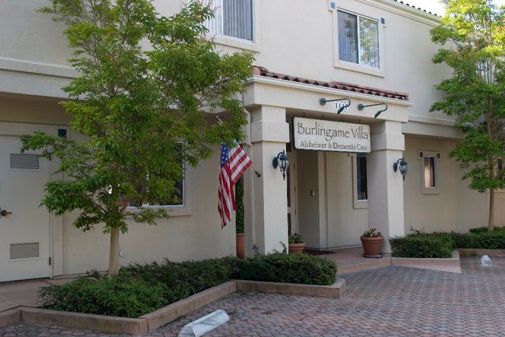 The entrance of a building with an American flag and potted plants.