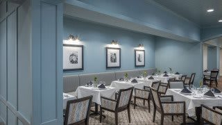 Elegant dining area with neatly arranged tables and framed artwork on the walls.