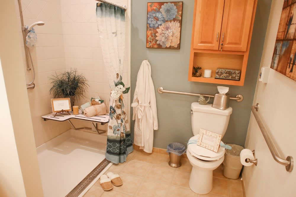 A cozy bathroom with a shower, toilet, and storage cabinet.