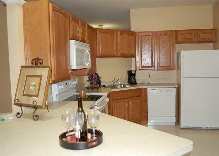 A modern kitchen with wooden cabinets, appliances, and a countertop featuring wine glasses.