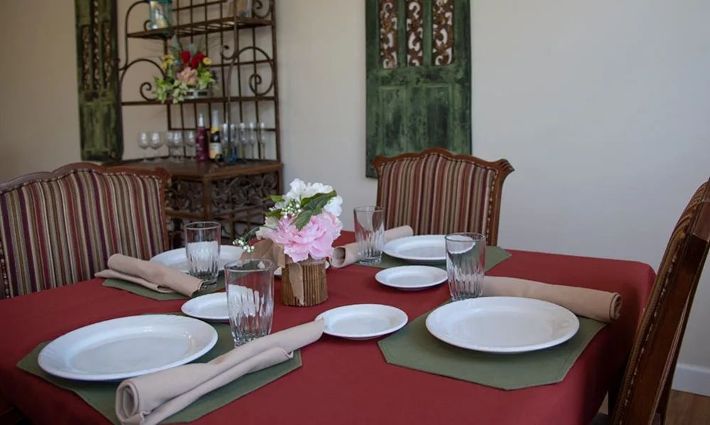 A dining table set with plates, glasses, napkins, and a floral centerpiece, ready for a meal.