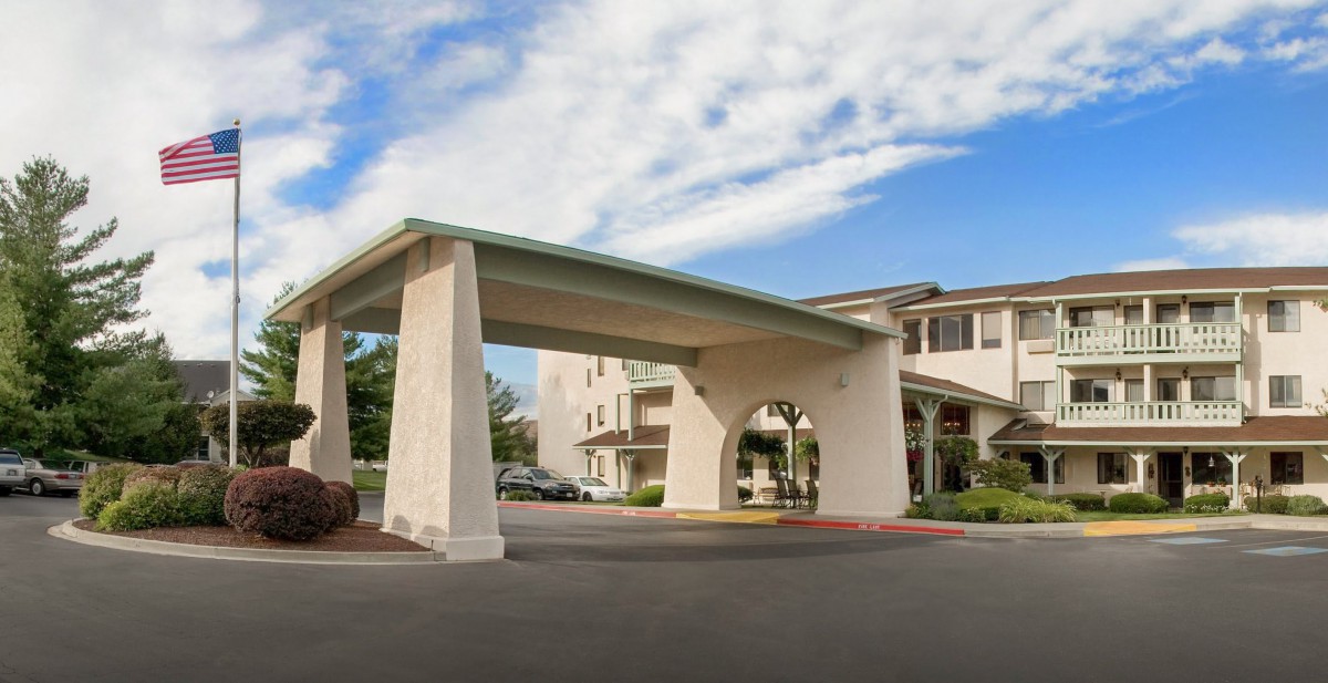Exterior view of a hotel with a covered entrance and clear skies above.