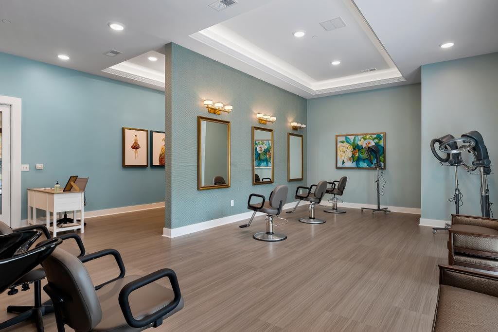 A modern hair salon interior with stylish chairs, mirrors, and artwork.