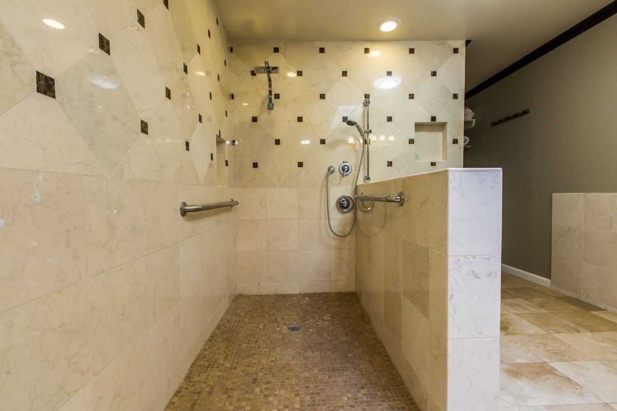 A modern, accessible walk-in shower with grab bars and stylish tiling.