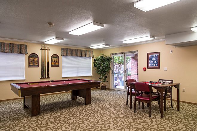 A cozy recreation room featuring a pool table, card table with chairs, and decorative wall art.