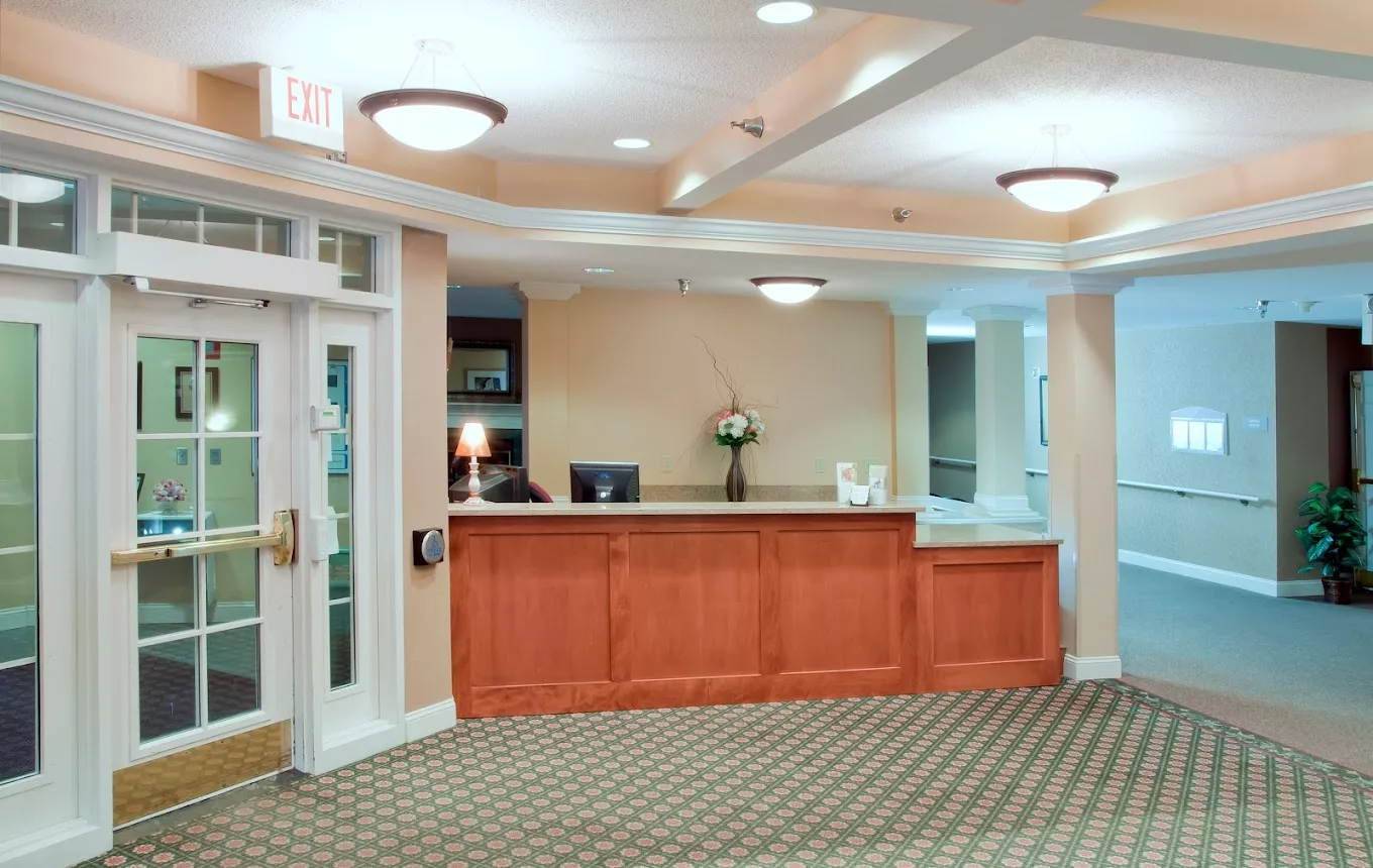 A well-lit reception area with a wooden desk and floral decor.