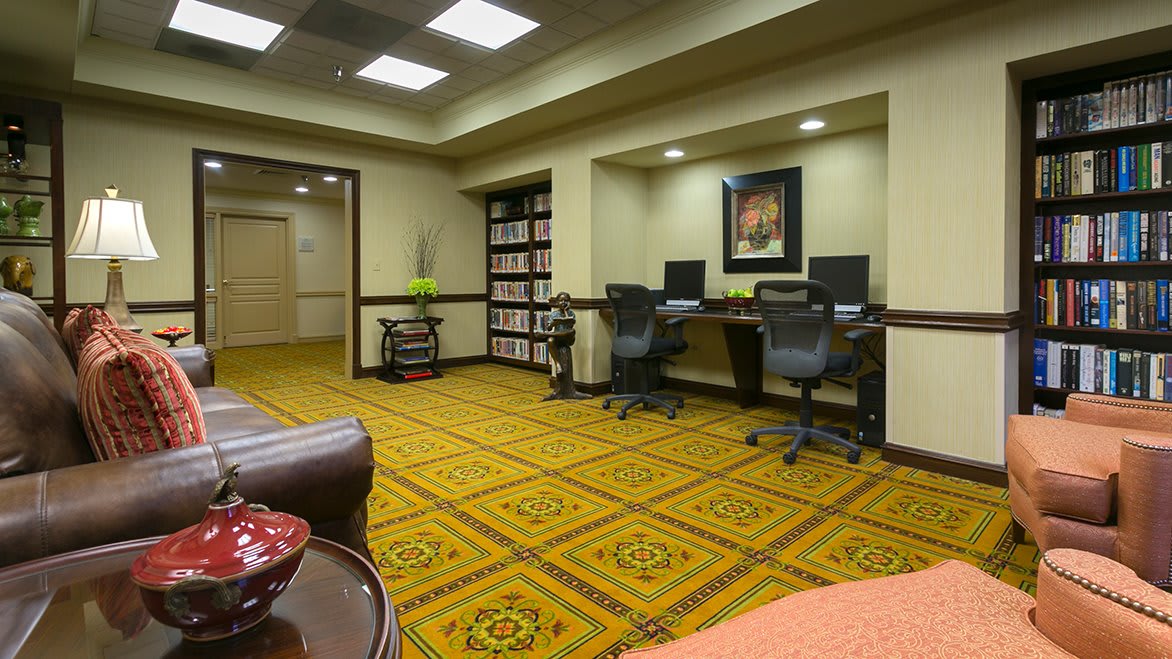 A neatly organized office space with two computer workstations and patterned carpeting.