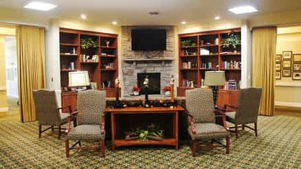 A cozy living room with a fireplace flanked by bookshelves and adorned with comfortable seating and lamps.