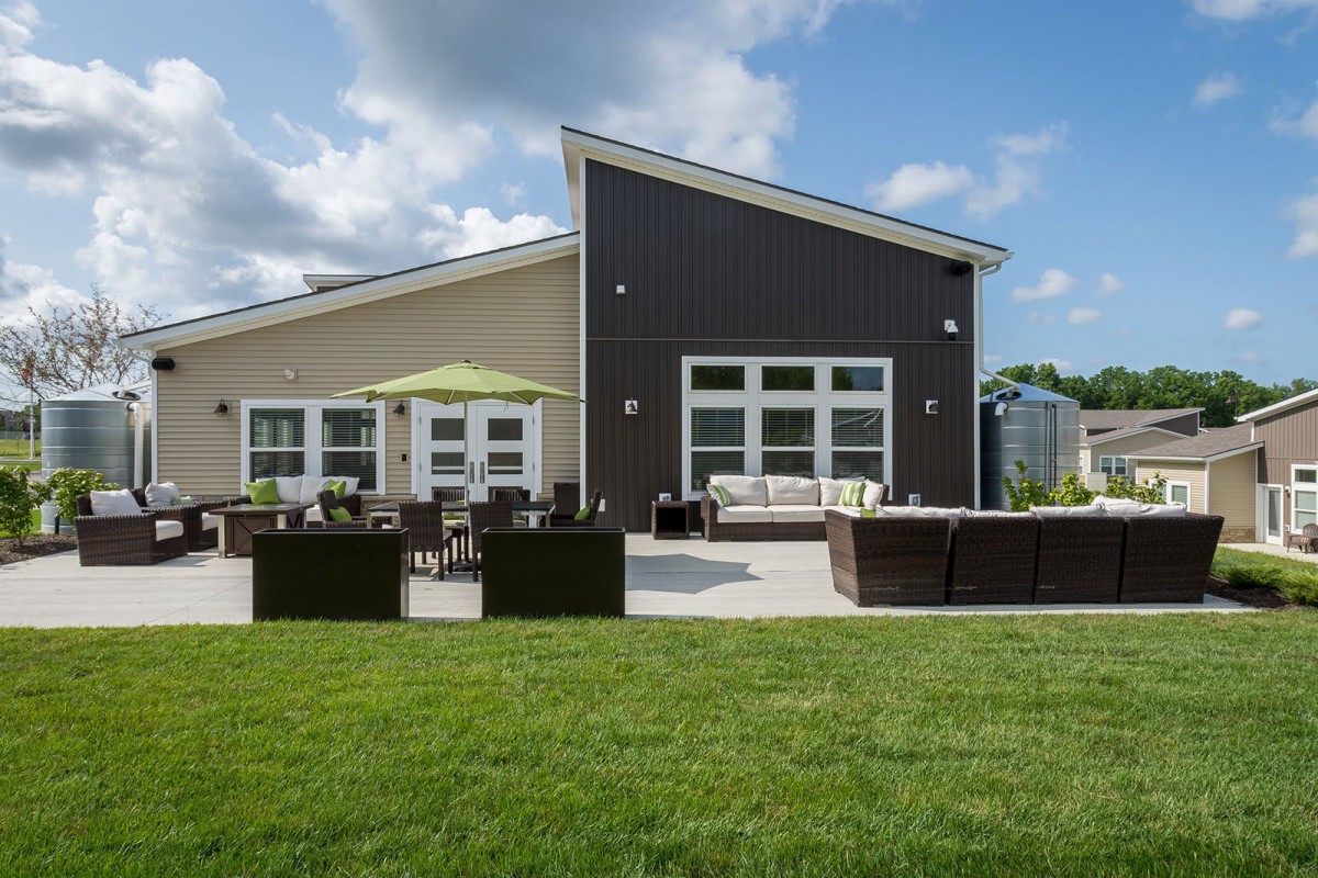 A modern house with a spacious patio and outdoor seating, surrounded by a well-maintained lawn on a sunny day.