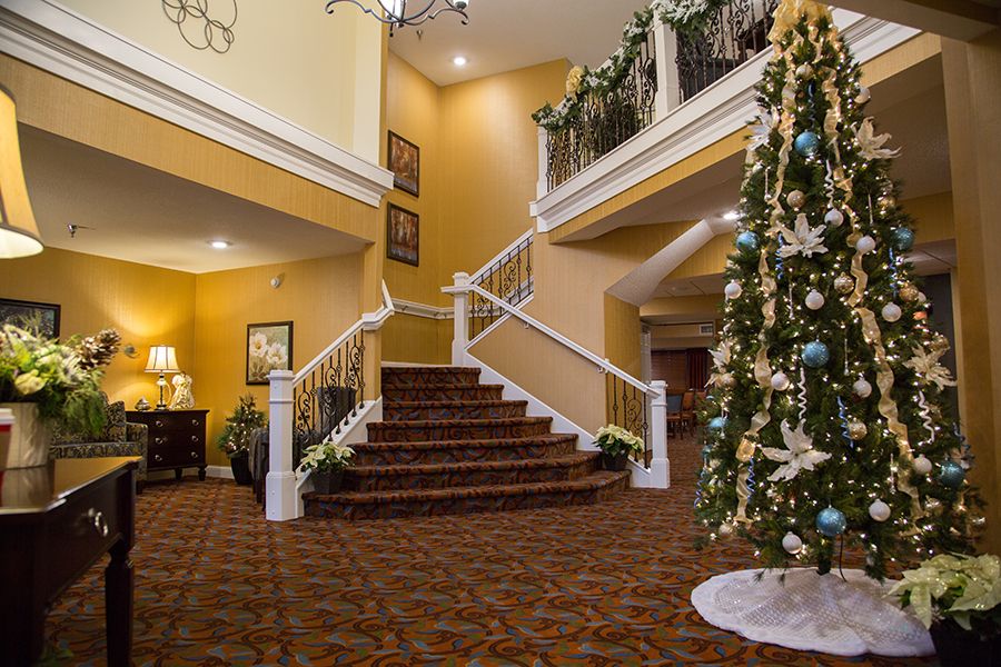A festive lobby with a decorated staircase and Christmas tree.