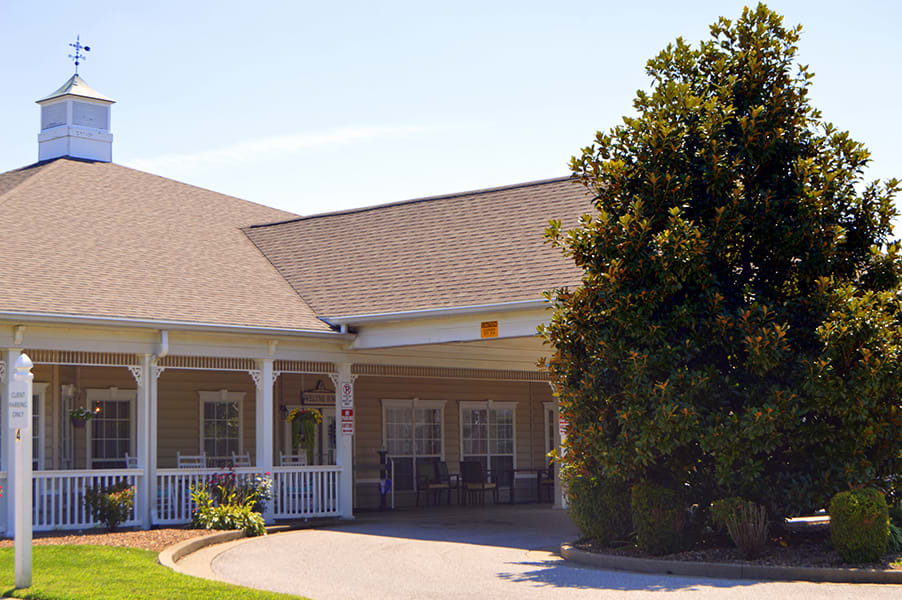 A suburban house with a porch and driveway surrounded by trees.