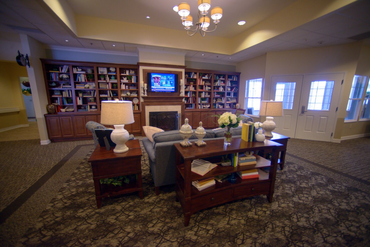 Cozy living room with a fireplace and bookshelves, featuring a sofa, coffee table, and decorative lamps.