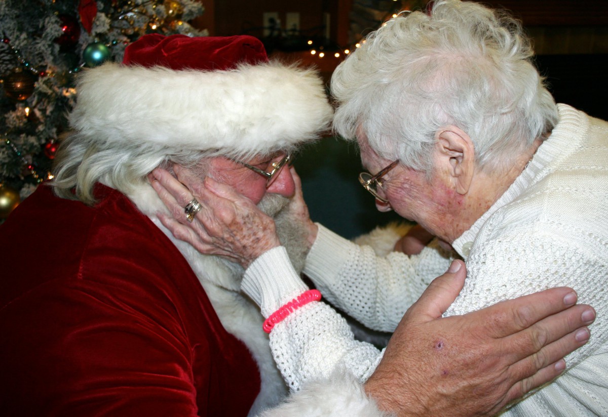 An emotional holiday moment between an elderly person and Santa Claus.