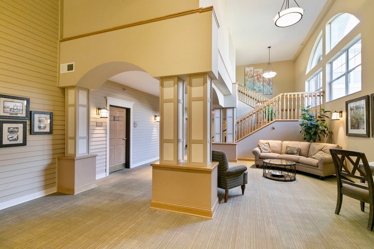 A modern lobby interior featuring a staircase, seating area, and stylish lighting fixtures.