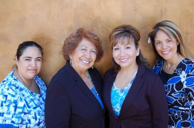 A group of women smiling in professional attire.