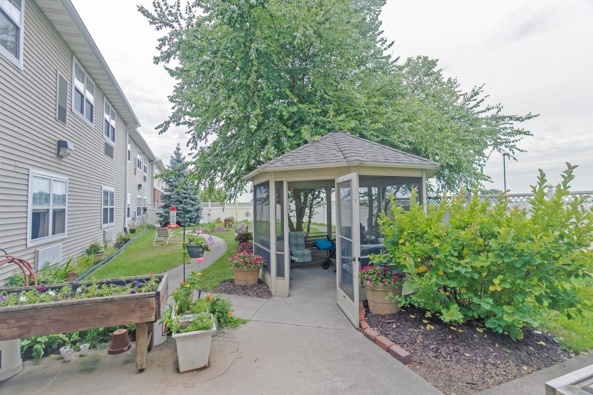 A serene garden area featuring a gazebo surrounded by lush greenery and a winding pathway.