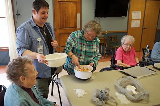A lively cooking activity taking place at a community center, where seniors are engaged in preparing a dish together.