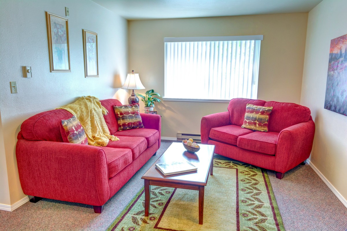 A cozy living room with red sofas, a coffee table, and decorative pillows.