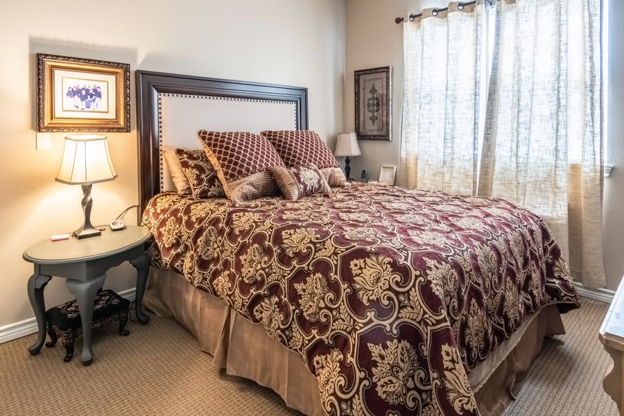 A cozy bedroom setup with a patterned comforter and several pillows on the bed.