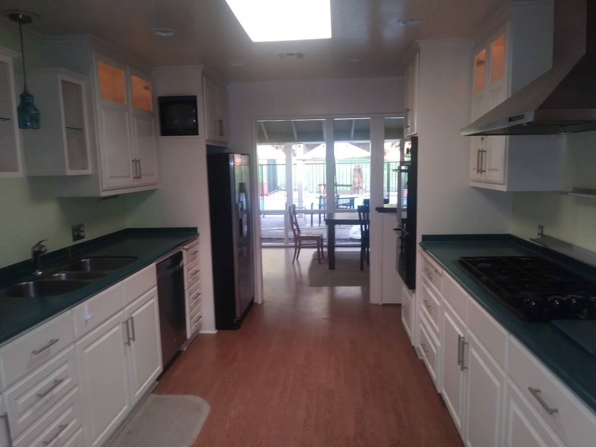 A modern kitchen with white cabinets and wood flooring, featuring a bright and open layout.