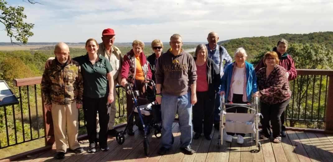 A group of people enjoying a sunny day outdoors, with some using mobility aids.