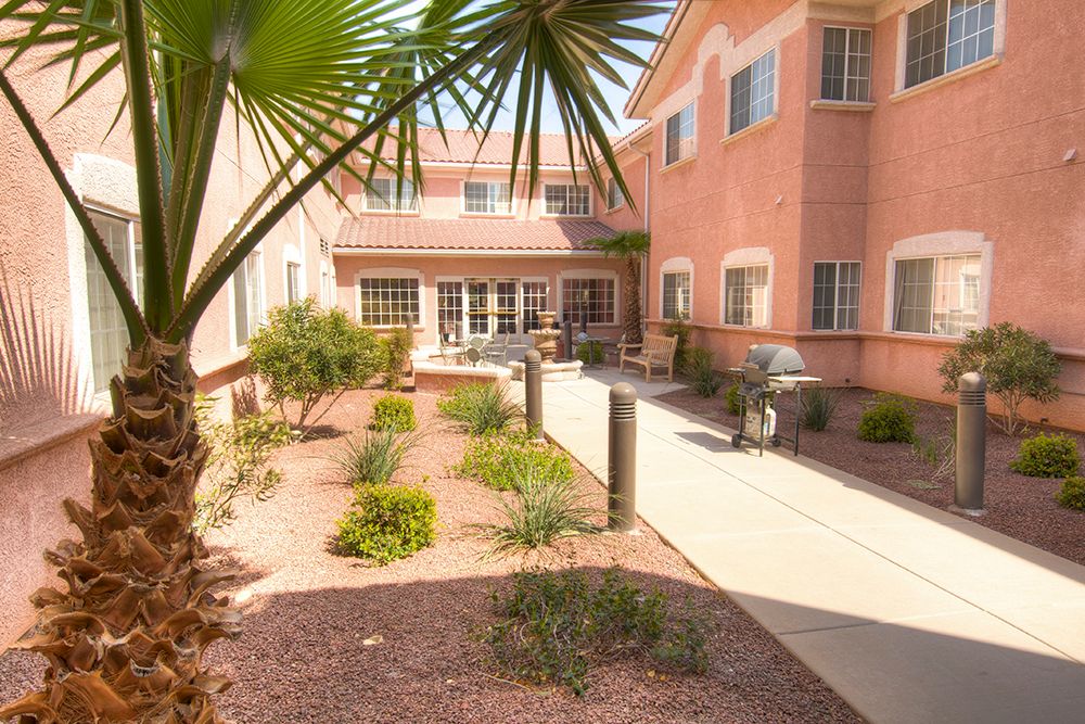 A sunny courtyard with desert landscaping and a paved walkway in a residential complex.