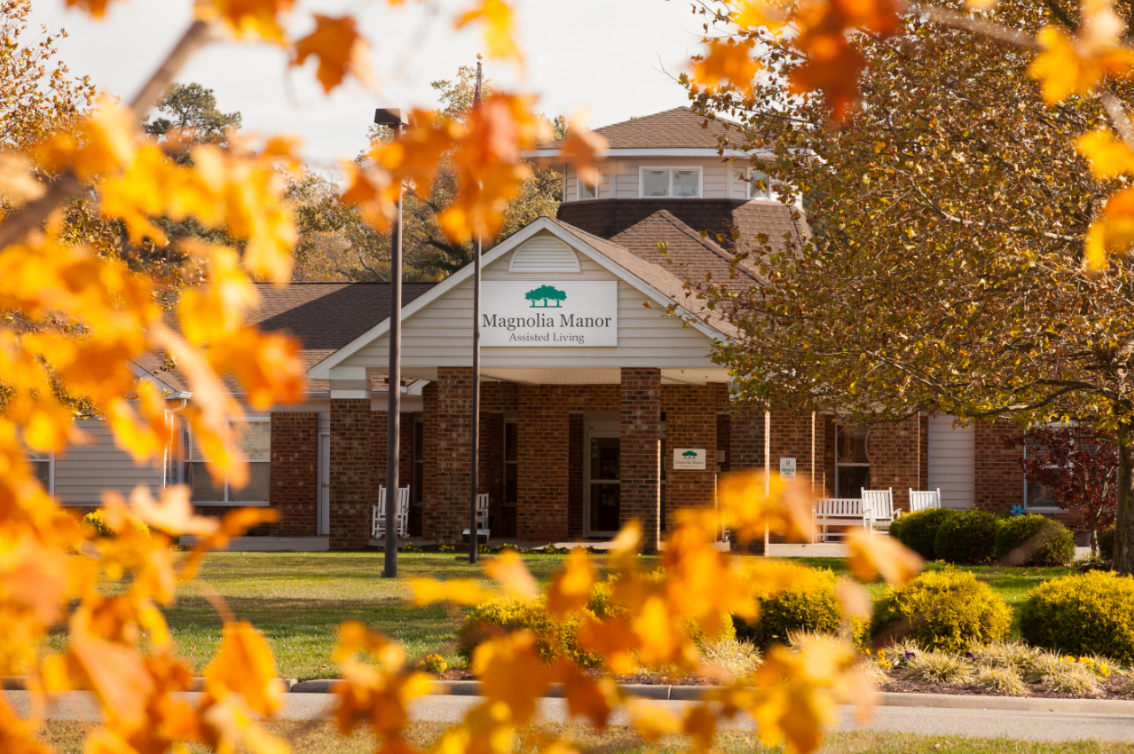 A building surrounded by colorful autumn leaves with a sign at the entrance.