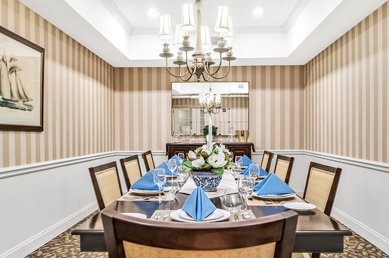 An elegantly arranged dining room with a formal table setting and chandelier.