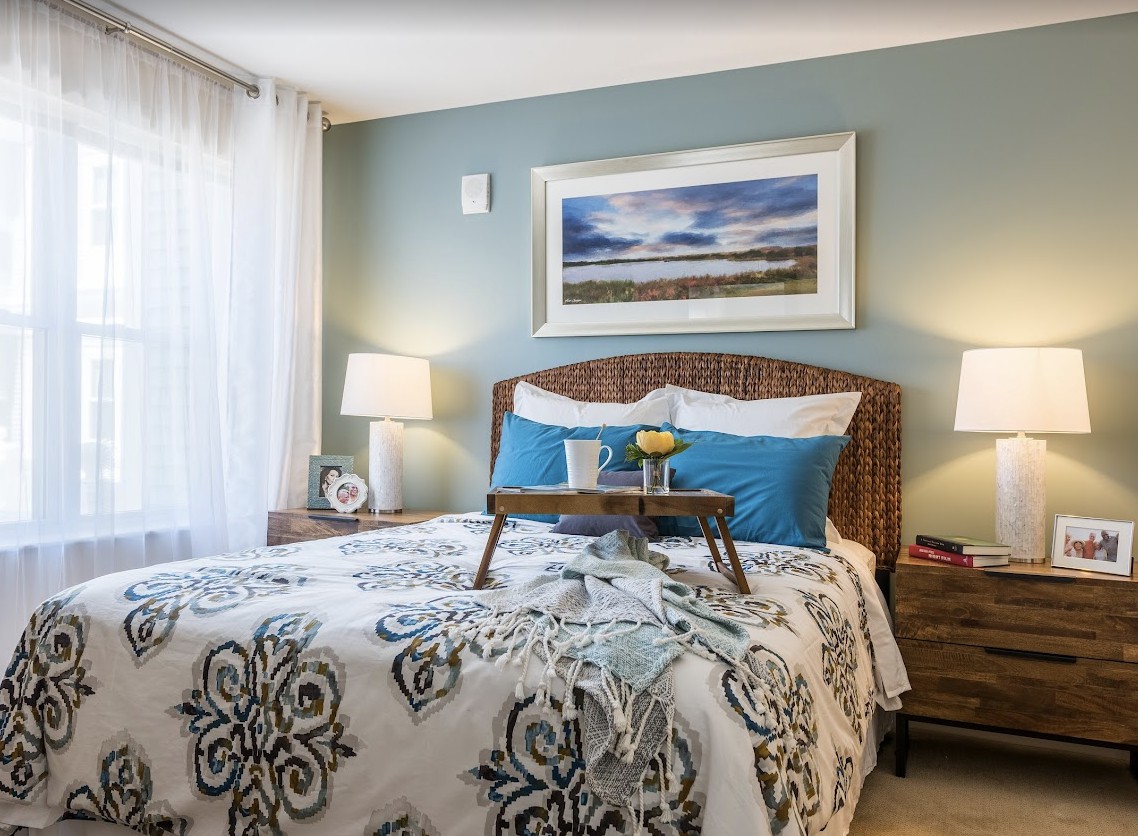 A cozy bedroom interior with decorative pillows, a patterned bedspread, and bedside lamps.
