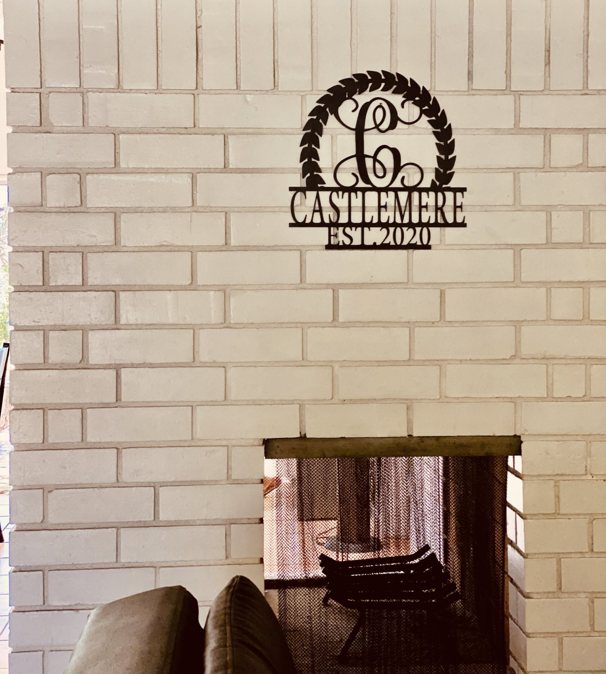 A cozy living room with a brick fireplace and a decorative metal sign above it.