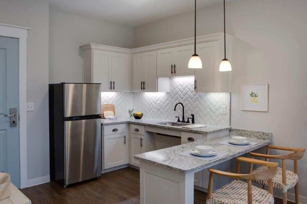 A modern kitchen with white cabinets, stainless steel appliances, and stylish pendant lights.