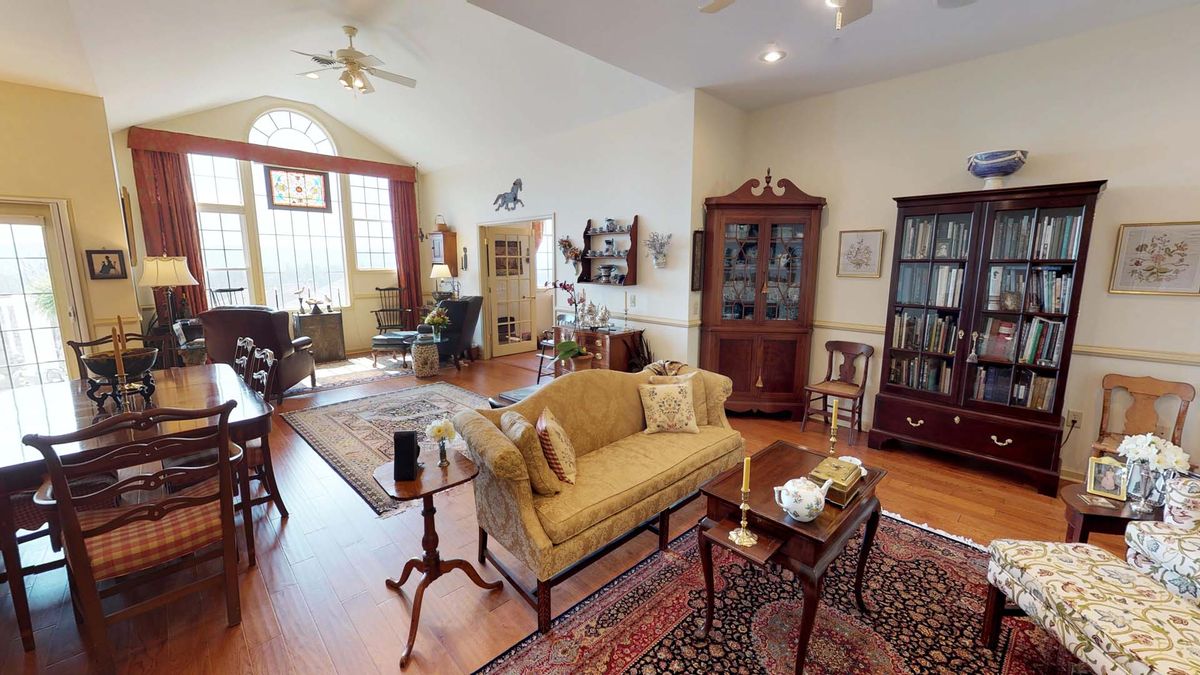 A traditionally styled living room with elegant furniture, featuring a sofa, coffee table, and bookshelves.