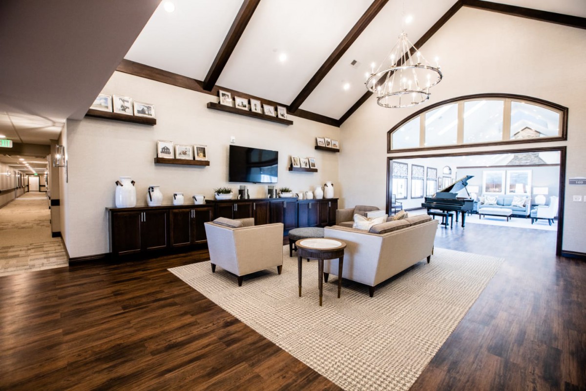 A modern and spacious living room with elegant furniture, a chandelier, and a grand piano.