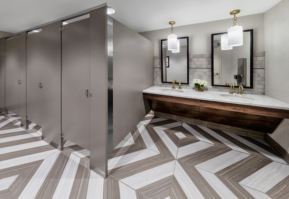 A modern public restroom featuring geometric floor tiles and minimalist design elements.
