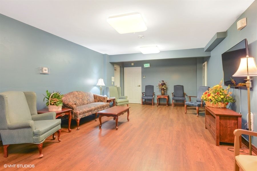A cozy living room with wooden flooring, comfortable seating, and decorative plants.