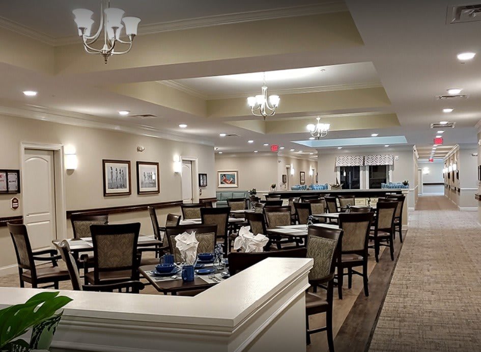 A stylish and elegant restaurant interior with neatly arranged tables and chairs, illuminated by chandeliers.