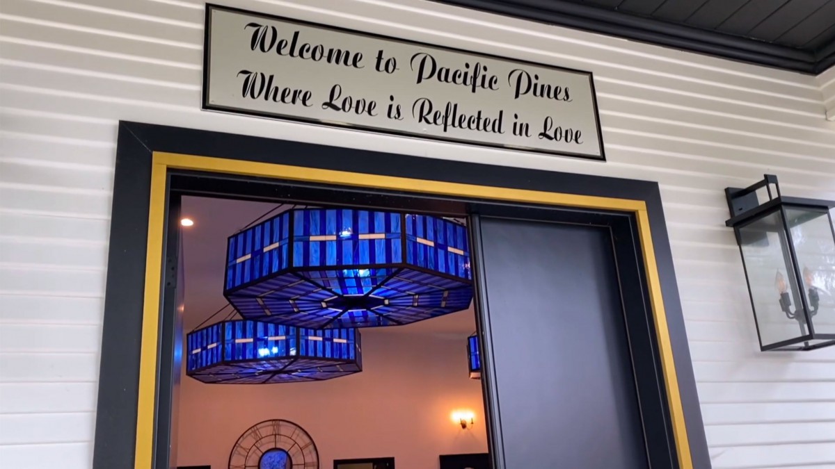 Entrance sign at Pacific Pines with blue lighting fixtures visible inside.