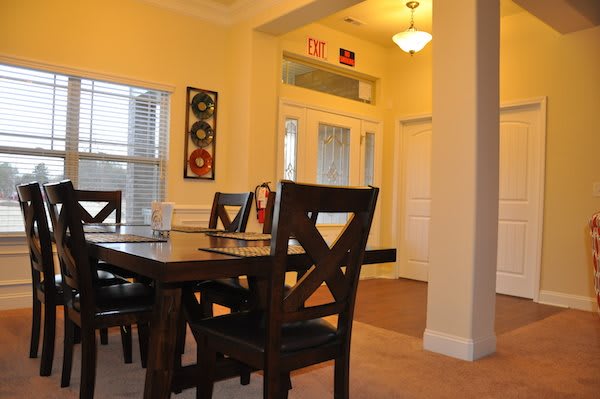 A cozy dining room with a wooden table and chairs, decorated with wall art and softly lit by a hanging light fixture.