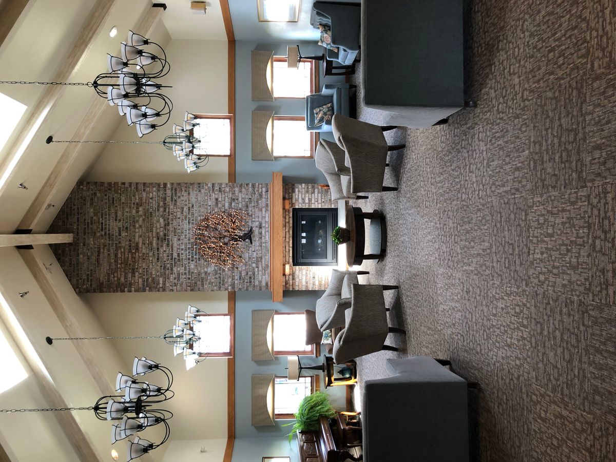 A spacious lobby featuring elegant chandeliers, a central stone fireplace, and comfortable seating arrangements.