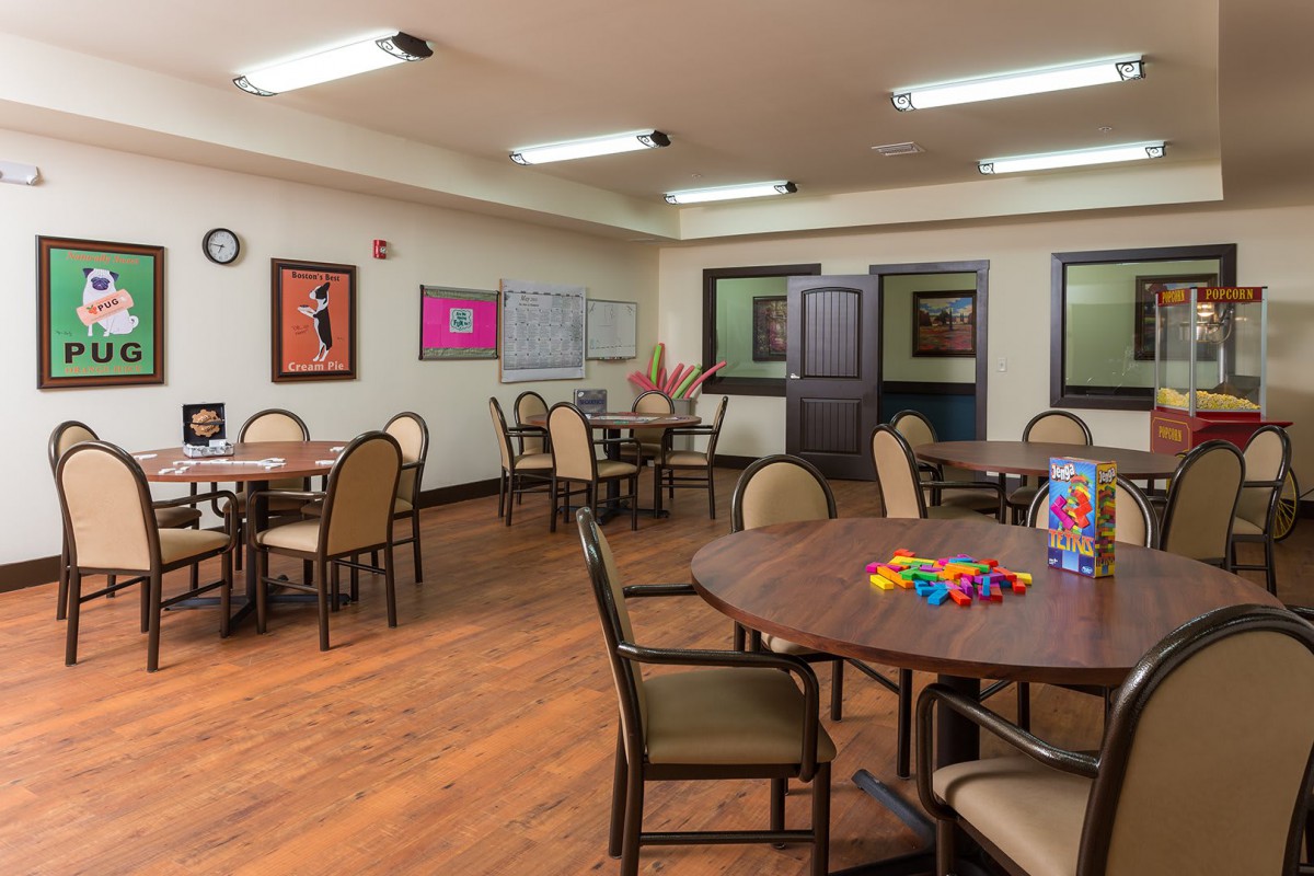 A spacious activity room with multiple tables and chairs, set up for community gatherings.