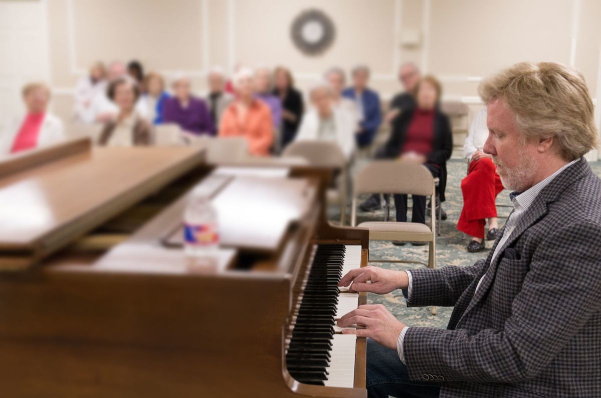 A musician performs on the piano for an attentive audience in a cozy setting.