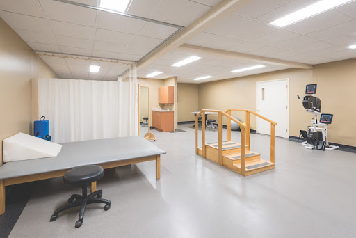 A spacious, well-lit room designed for therapy or rehabilitation, featuring a set of stairs and a workspace.
